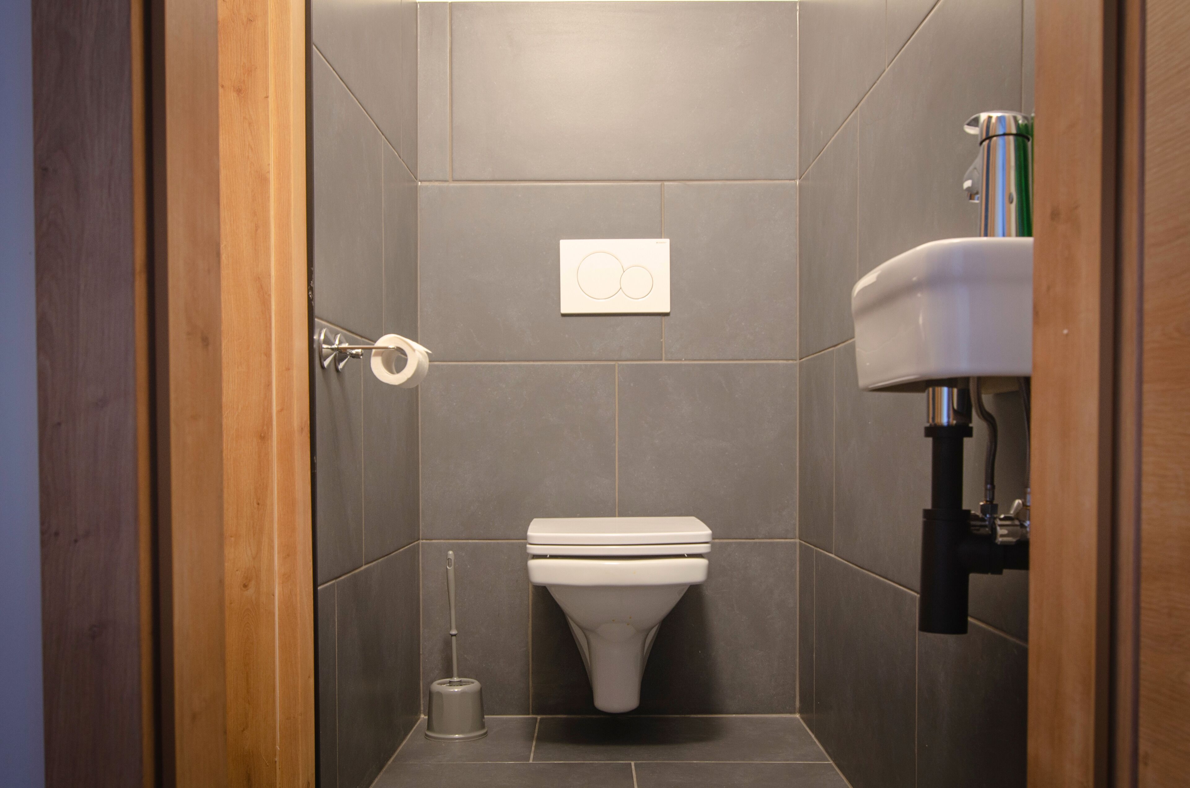 A bathroom with a toilet, a hand dryer, and a sink.