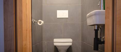 A bathroom with a toilet, a hand dryer, and a sink.