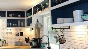 Una cocina moderna con gabinetes blancos, una encimera de madera y un microondas integrado.