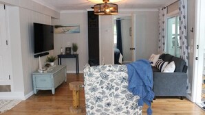 Una sala de estar con un sofá estampado, un sofá gris, un televisor y una mesa de centro de madera.