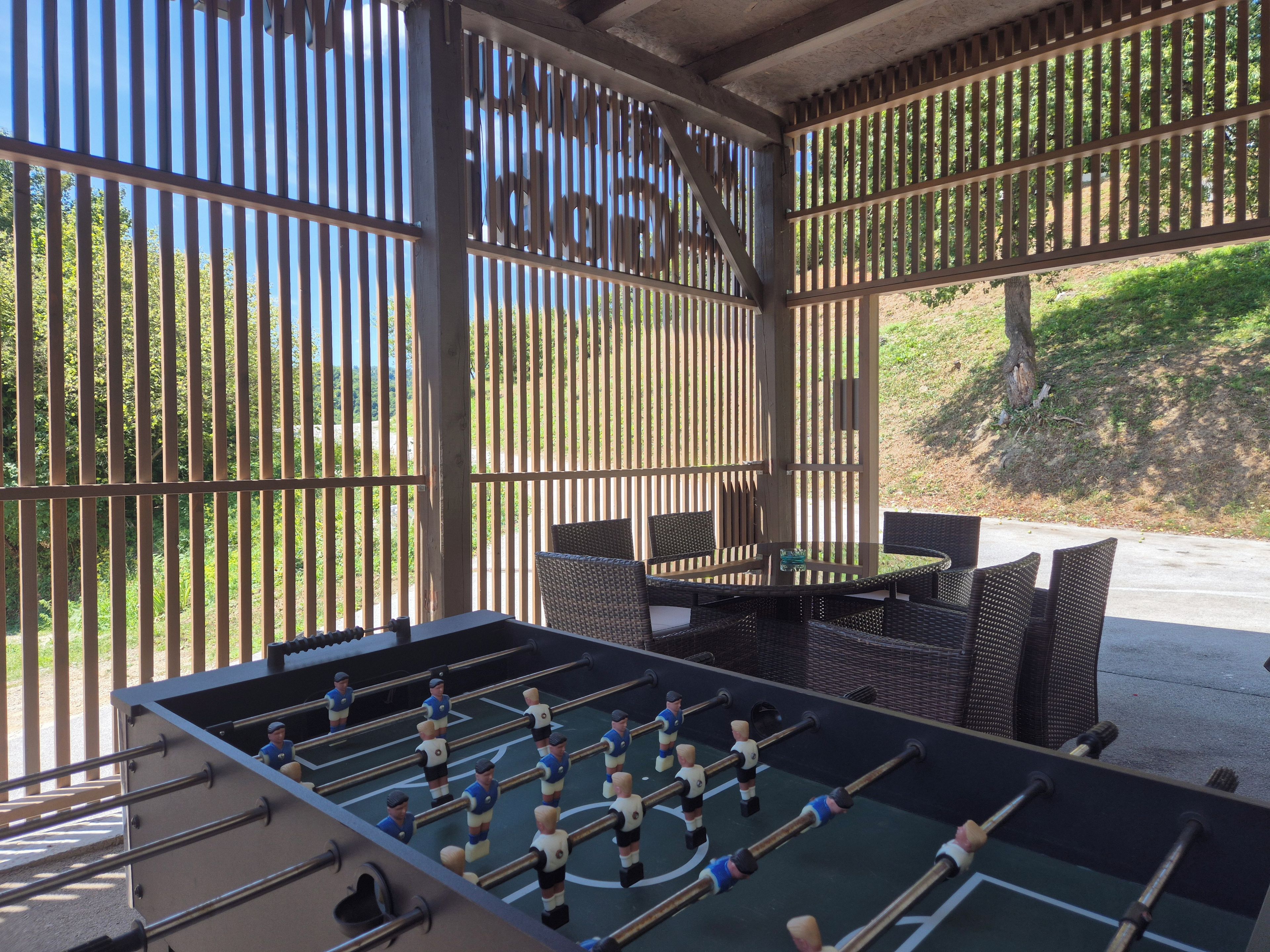 Zona salotto all'aperto con tavolo da calcio e vista su una zona boschiva.
