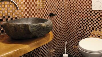 Een badkamer met een wastafel van steen, een toilet en een wastafel met een kraan.