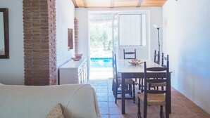 A dining area with a table and chairs, a brick wall, and a view of a swimming pool. - Cubo's Finca Sanchez Aranda / Private swimming pool / free wifi (Alhaurín el Grande)