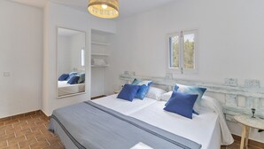 Une chambre à coucher avec un lit, un luminaire suspendu, une fenêtre et un miroir.