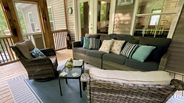 A covered porch with a wicker chair, a sofa with patterned cushions, and a small table with a plant. - Pet-Friendly Lakefront Retreat • Hot Tub, Sandy Shore & Fenced Yard (Westminster)