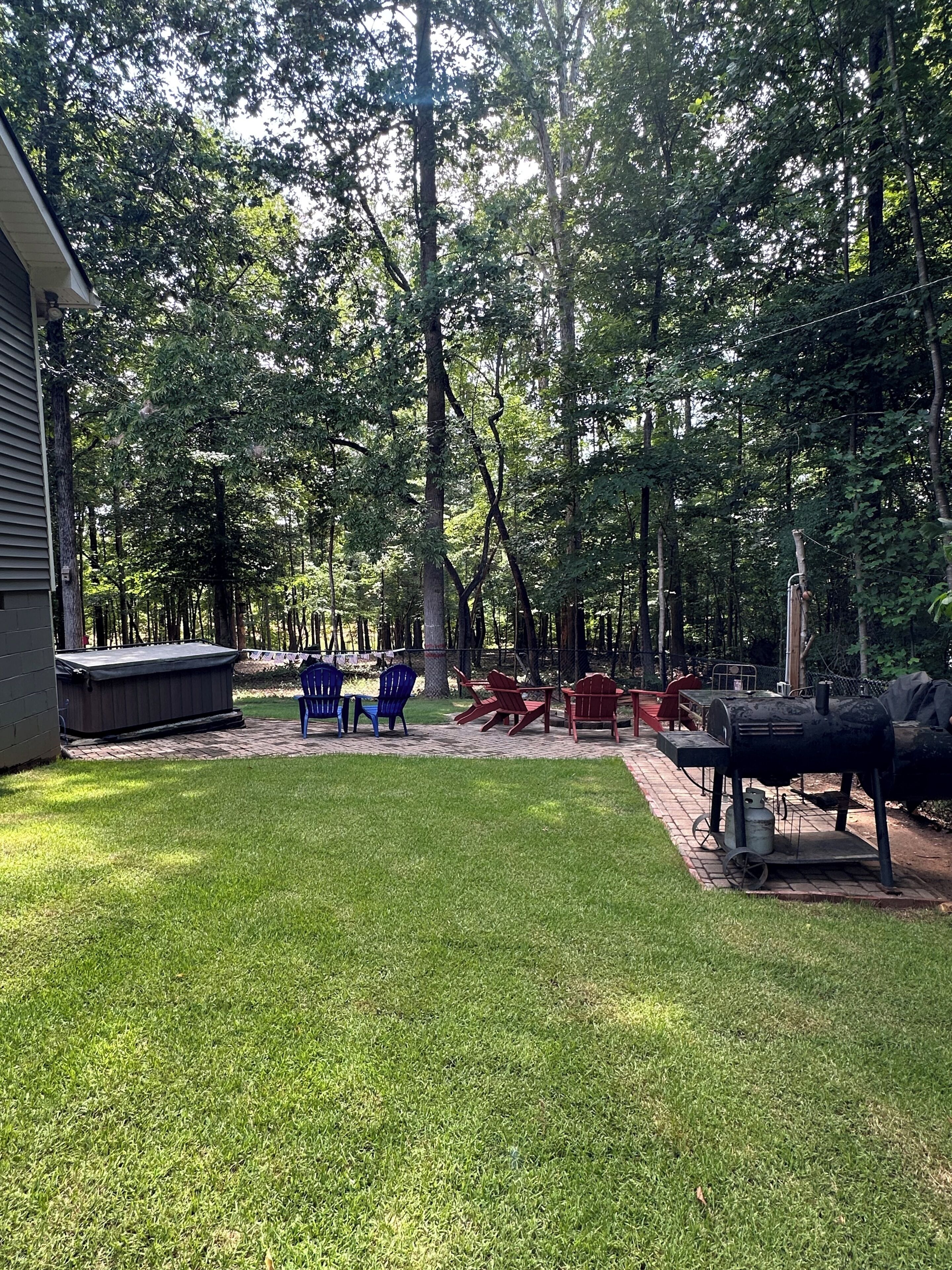 Ein Garten mit Whirlpool, Gartenmöbeln und Grill.