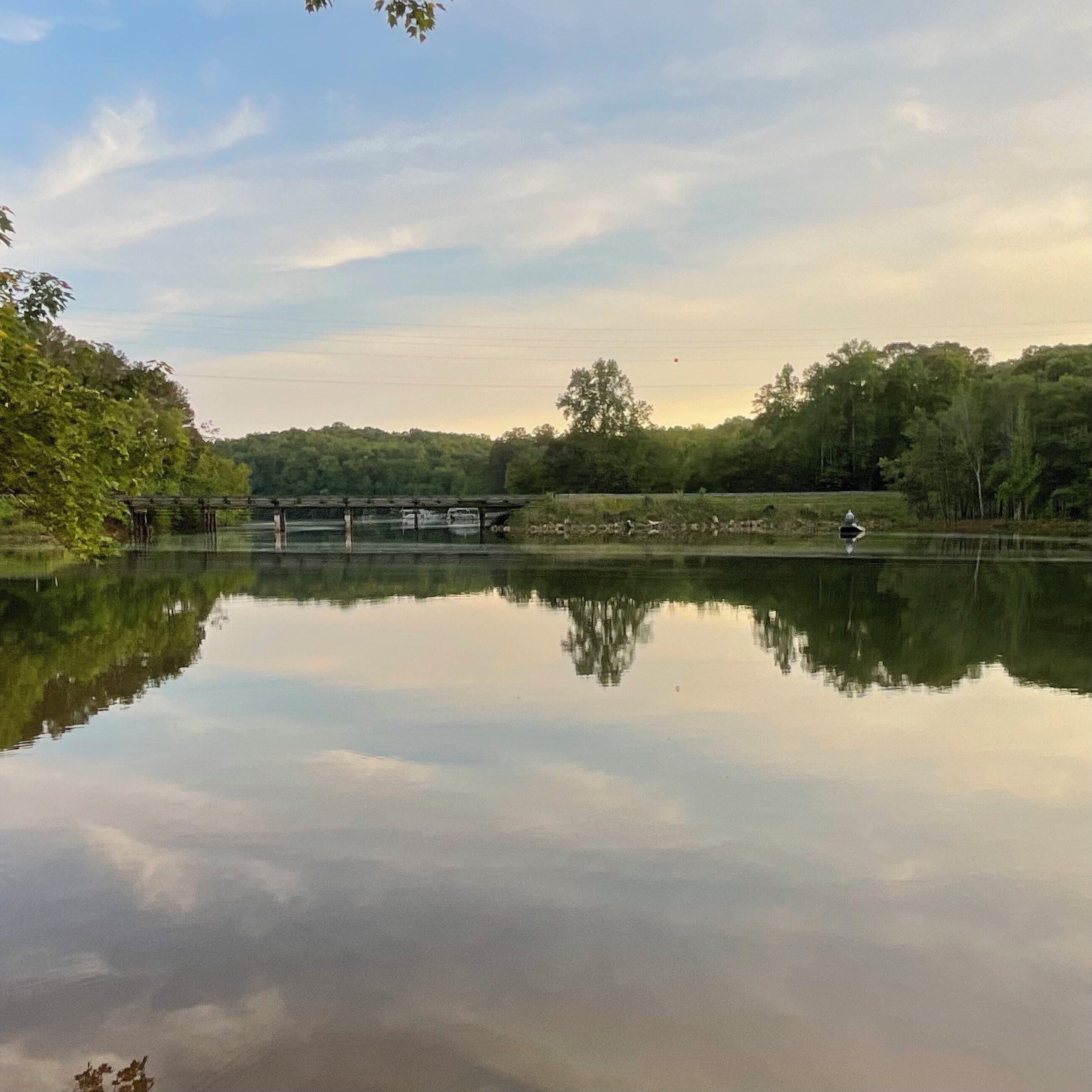 Un lac paisible, avec un pont en bois et un kiosque au centre.
