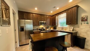 A modern kitchen with dark wooden cabinets, stainless steel appliances, and a large island with stools. - Pet-Friendly Lakefront Retreat • Hot Tub, Sandy Shore & Fenced Yard (Westminster)