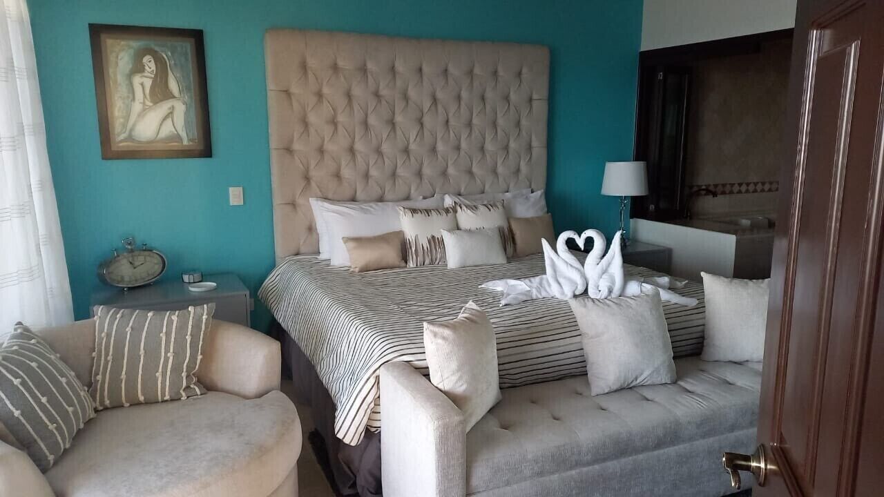 Une chambre d’hôtel avec un grand lit, un canapé, une table de chevet avec une horloge et un tableau au mur.
