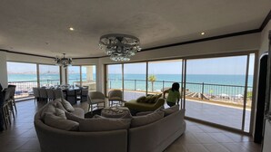 Un soggiorno ampio con un divano spazioso, zona pranzo e un balcone vista mare.