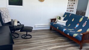 Ein Wohnzimmer mit einer Couch, einem Sessel, einem Tisch und einem Wandbild einer Landschaft.