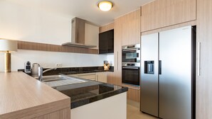 A modern kitchen with a stainless steel refrigerator, built-in oven, and a granite countertop. - Fantastic ocean view apartment on Blue Bay (Sint Michiel)