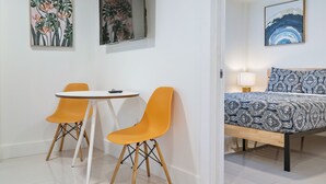 Une pièce comprenant un lit, deux fauteuils orange, une petite table et deux œuvres d’art encadrées accrochées au mur.