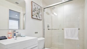 Une salle de bain moderne avec un meuble-lavabo blanc, des toilettes et une douche à parois de verre.