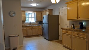 A kitchen with wooden cabinets, a stainless steel refrigerator, a microwave, and a coffee maker.