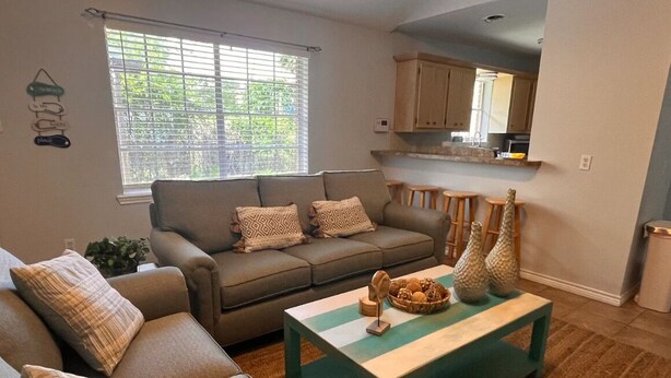 A living room with a sofa, coffee table, and a window with blinds.