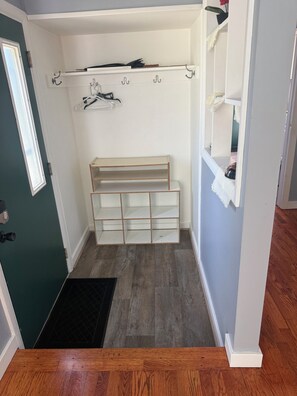 A walk-in closet with open shelving, a shoe rack, and a small bench.