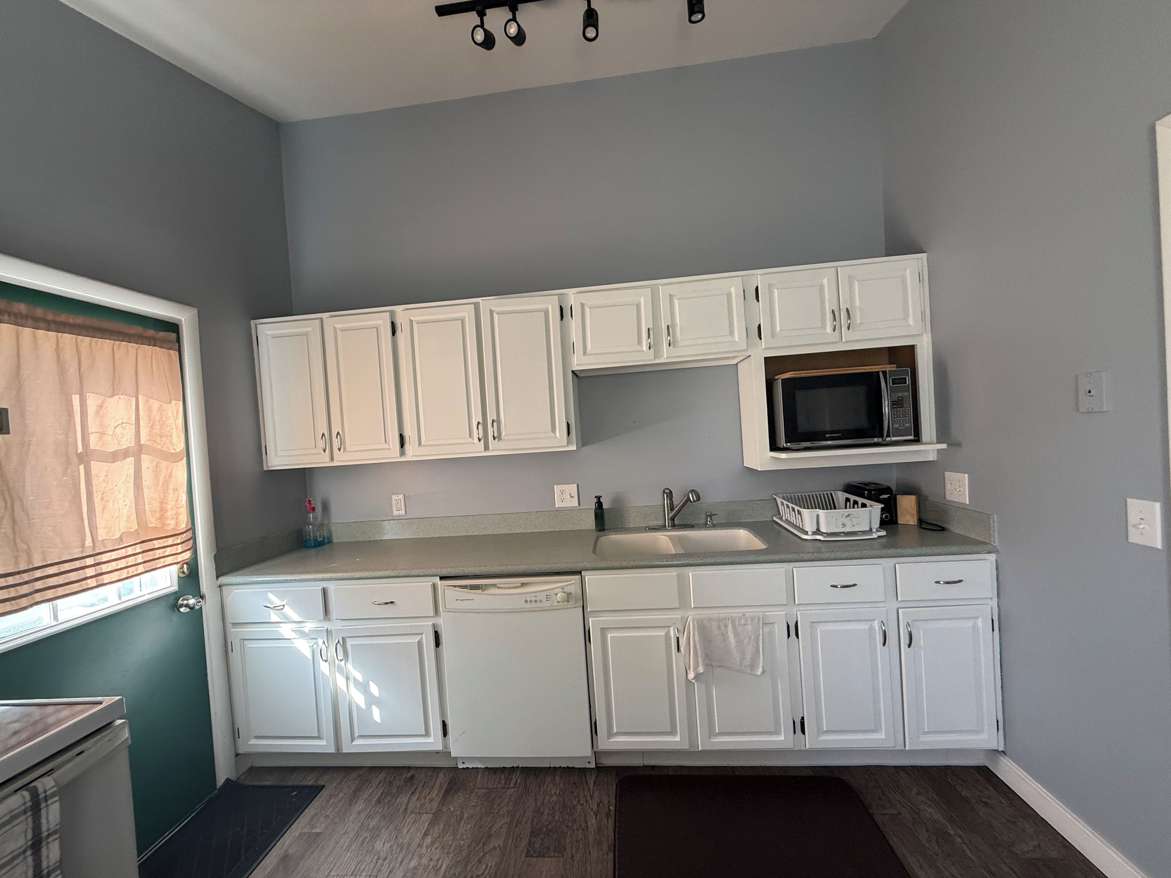 A kitchen with white cabinets, a microwave, and a dishwasher.