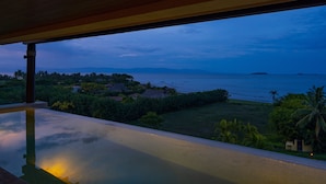 Un balcon offrant une vue sur un paysage côtier, comprenant une étendue d’eau et des îles au loin.