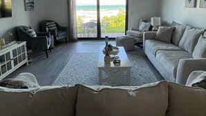 Een woonkamer met een groot raam, een plafondventilator en een bank.