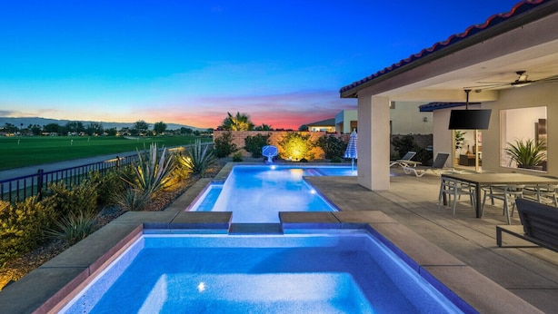 A swimming pool area with two pools, a patio with outdoor furniture, and a view of a golf course. - Private pool & putting green - PGA WEST (La Quinta)