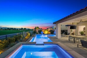 Un espace piscine comprenant deux piscines, un patio avec mobilier d’extérieur et une vue sur un terrain de golf.