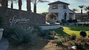 A building with a stone wall and a sign that reads "Signature at PGA West." - Private pool & putting green - PGA WEST (La Quinta)