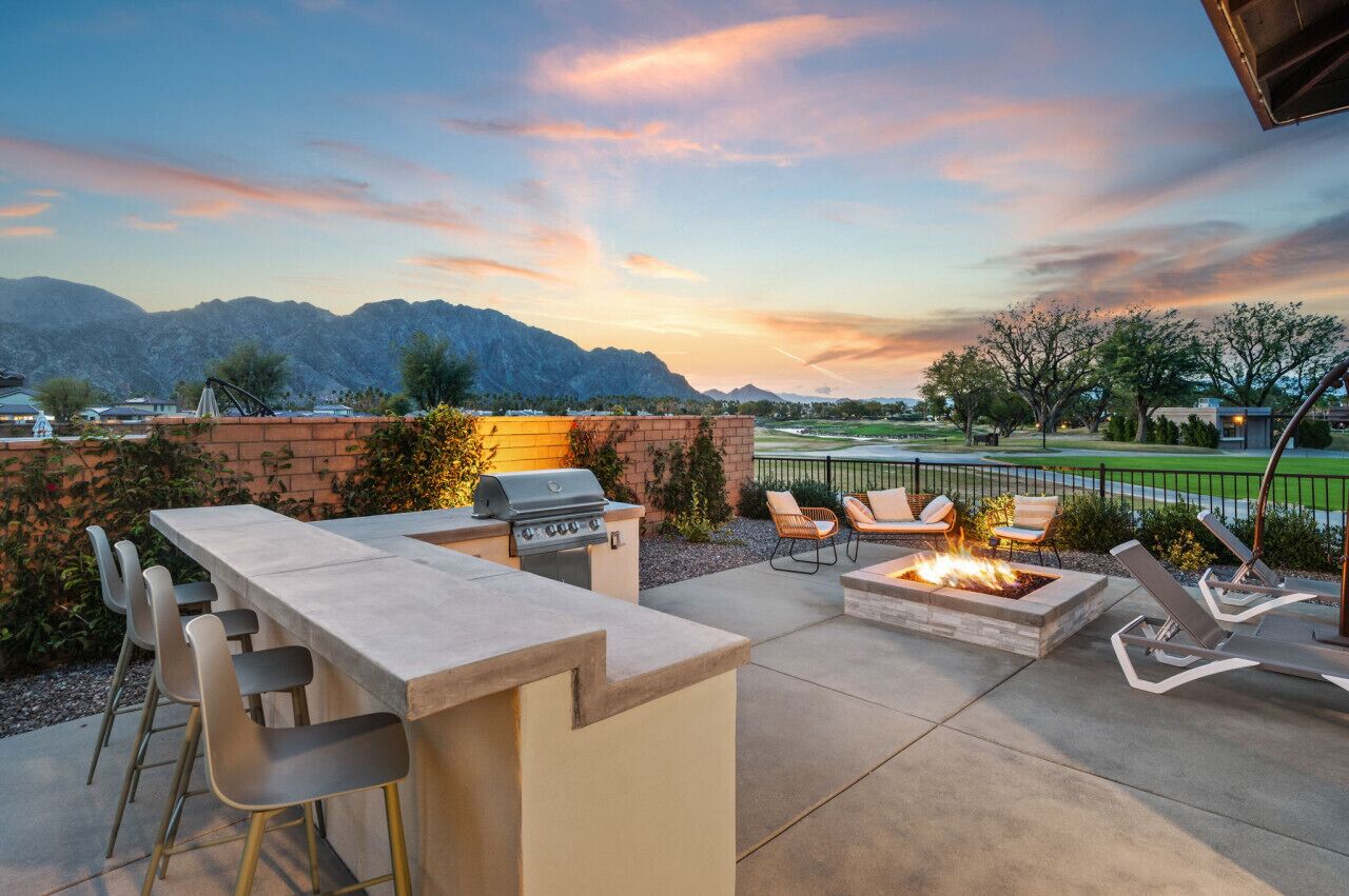 An outdoor patio with a barbecue grill, seating area, and a view of mountains.