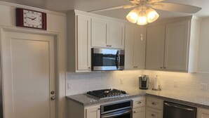 A kitchen with white cabinets, a stainless steel microwave, a gas stove, an oven, and a dishwasher. - The “Clubhouse” in the Village of Arroyo Grande (Arroyo Grande)