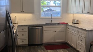 A modern kitchen with white cabinets, a stainless steel refrigerator, a dishwasher, a window with a view, and a ceiling fan. - The “Clubhouse” in the Village of Arroyo Grande (Arroyo Grande)