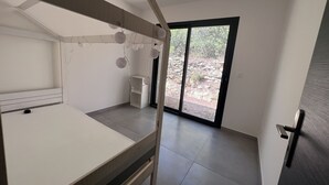 A bedroom with a bunk bed, a small bedside table, a wardrobe, and a sliding glass door leading to an outdoor area. - Villa Avec Jacuzzi la Cadiere Dazur (La Cadière-d'Azur)
