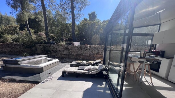 An outdoor patio with a hot tub, lounge chairs, and a stone wall. - Villa Avec Jacuzzi la Cadiere Dazur (La Cadière-d'Azur)