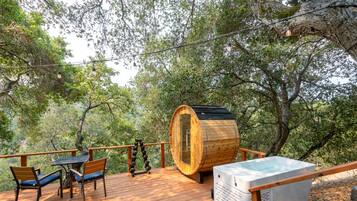 Eine Holzterrasse mit Gartenmöbeln, einer Sauna und einer Holzbottlei.