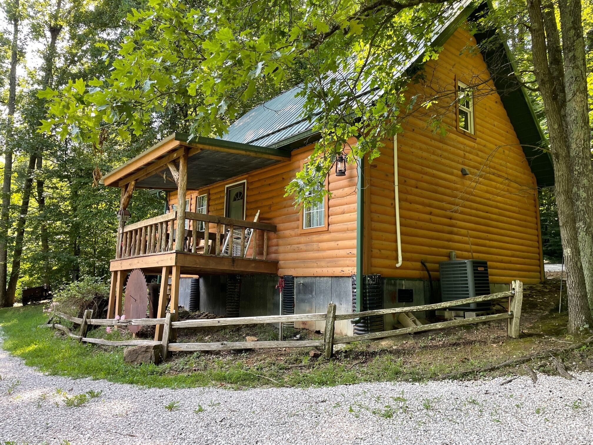 A log cabin with a balcony, surrounded by trees.