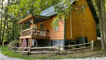 A log cabin with a balcony, surrounded by trees.