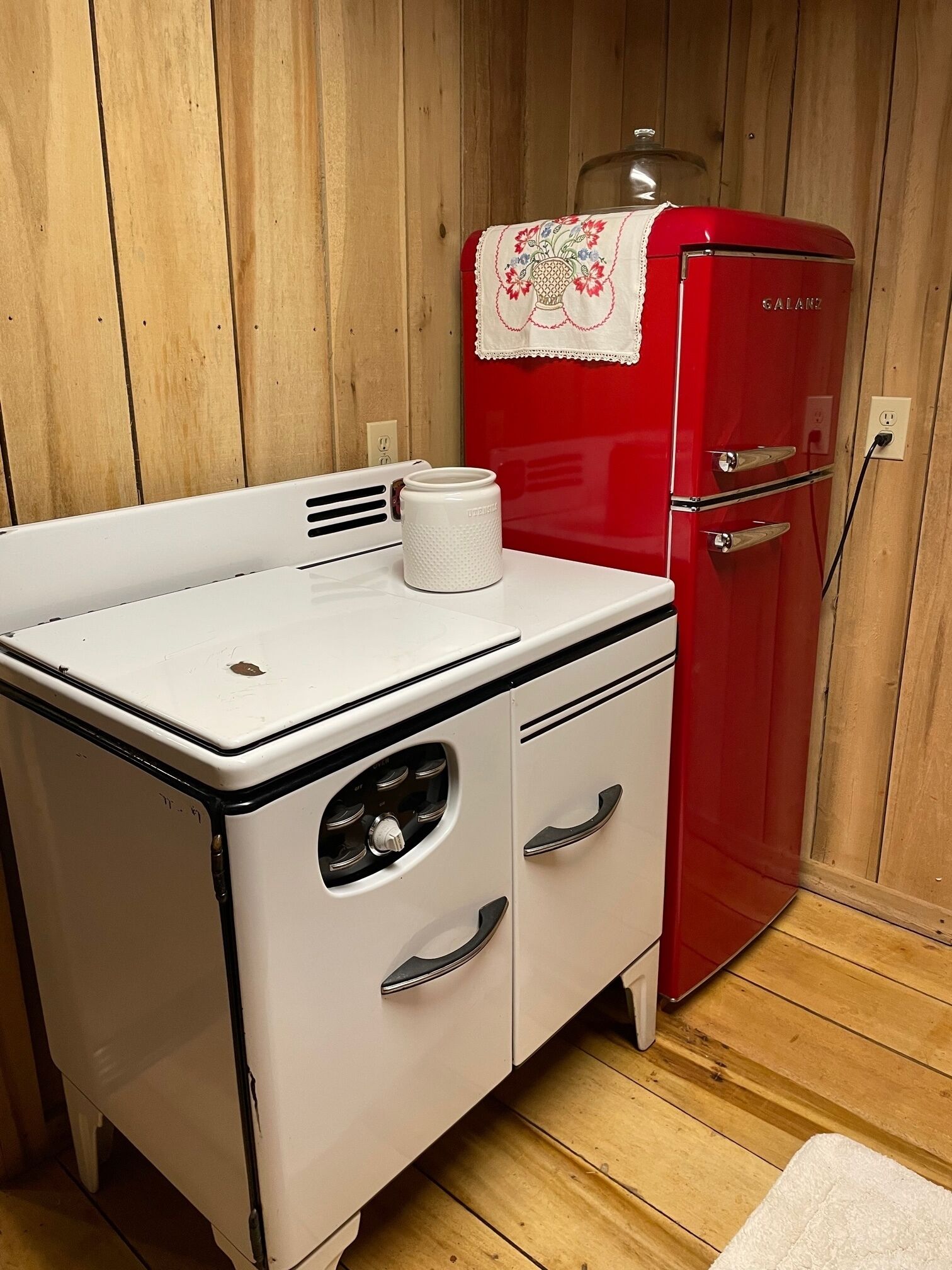 Une petite cuisine équipée d’une cuisinière blanche et d’un réfrigérateur rouge.
