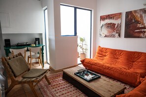 A living room with a wooden coffee table, orange sofa, and a dining area with a table and chairs.