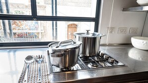 Une cuisine équipée d’appareils électroménagers en acier inoxydable, une fenêtre donnant sur des immeubles et un saladier blanc posé sur le plan de travail.