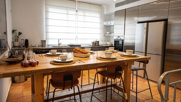 Une cuisine moderne avec un îlot central en bois, des appareils électroménagers en acier inoxydable et une grande fenêtre.