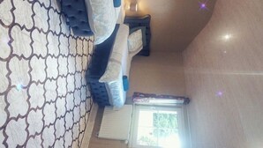 Une pièce avec un lit, une petite table et une chaise. Il y a une fenêtre donnant sur un paysage verdoyant.
