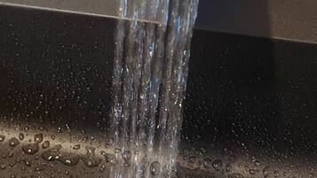 Un robinet d’où coule de l’eau dans un lavabo.