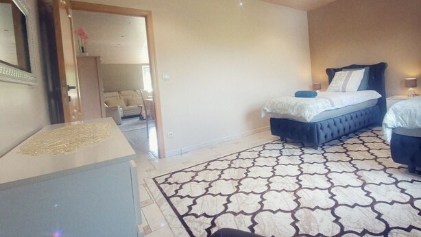 Une chambre à coucher comprenant un lit, des tables de chevet, une commode, un tapis à motifs et un miroir.