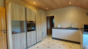 Une cuisine compacte avec des meubles de rangement en bois, un four encastré, un évier et un plan de travail.