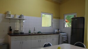 A kitchen with white cabinets, a stove, a sink, and a window. - Nice & private in our backyard with own entry & parking lot. (Willemstad)