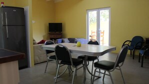 A dining area with a table, chairs, a refrigerator, and a television. - Nice & private in our backyard with own entry & parking lot. (Willemstad)
