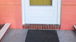 A white door with a yellow window, a number '3909' on the wall, and a 'WELCOME' mat.