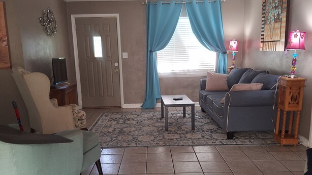 A living room with a sofa, a coffee table, a TV, and a door.