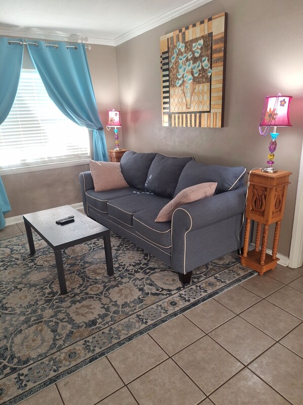 A living room with a sofa, a coffee table, a lamp, and a rug.