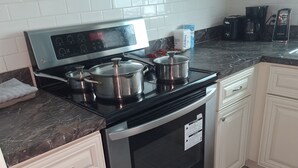 A kitchen with a stainless steel stove, white cabinets, and a tiled backsplash.