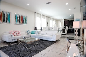 A modern living room with a white sofa, a glass coffee table, and abstract art on the walls.